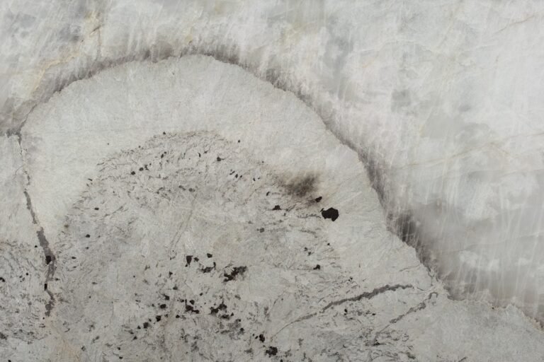 Patagonia Crystal quartzite slab — white crystalline stone with a dramatic grey halo vein and dark garnet accents, in stock at KJM Stones in Buda, TX