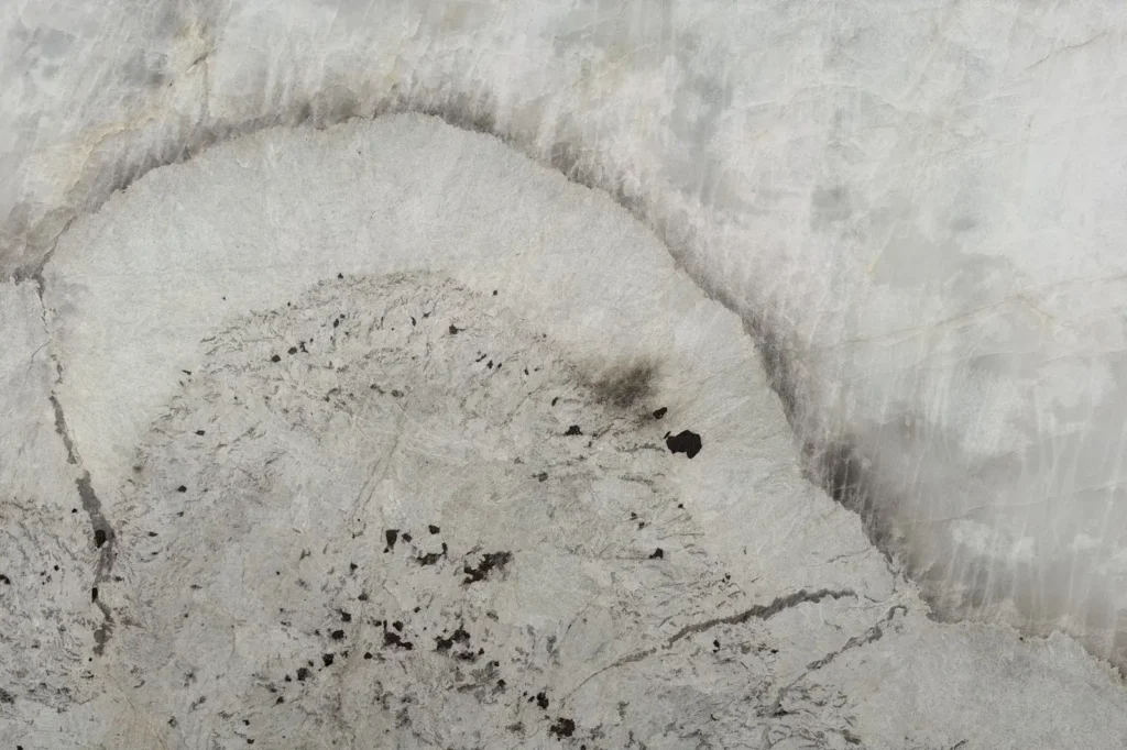 Patagonia Crystal quartzite slab — white crystalline stone with a dramatic grey halo vein and dark garnet accents, in stock at KJM Stones in Buda, TX